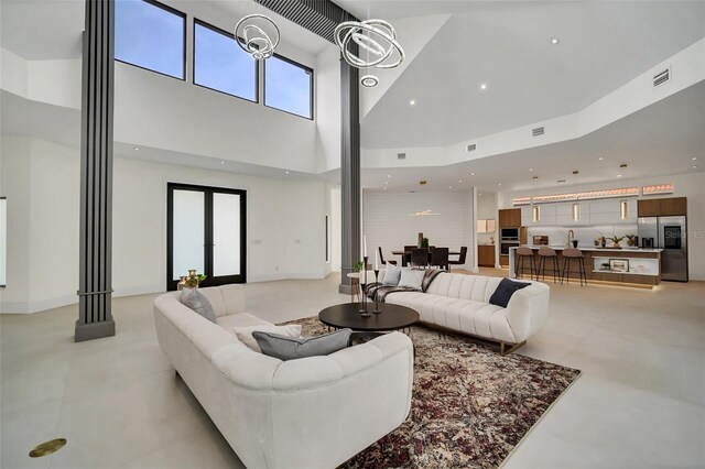 living room with a high ceiling, a wealth of natural light, french doors, and sink