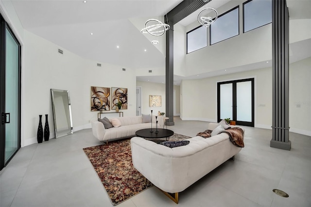 living room featuring a healthy amount of sunlight, a towering ceiling, french doors, and a notable chandelier