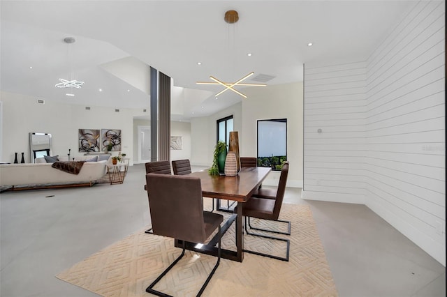 dining area with an inviting chandelier and wood walls