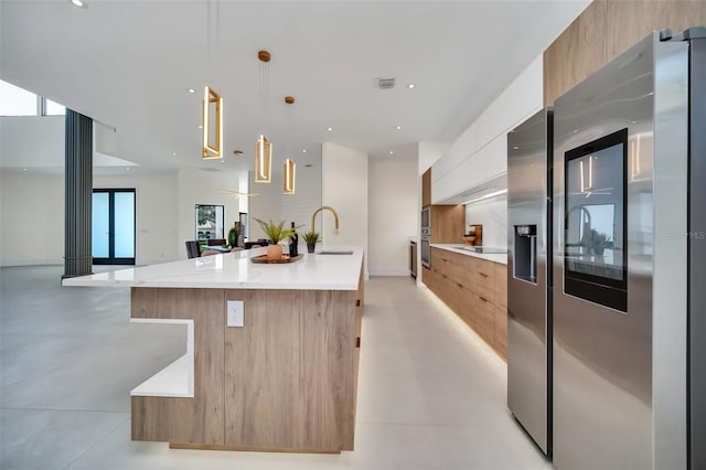 kitchen featuring sink, a large island, decorative light fixtures, white cabinetry, and stainless steel appliances