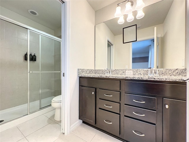 bathroom with vanity, a shower with shower door, tile patterned floors, and toilet