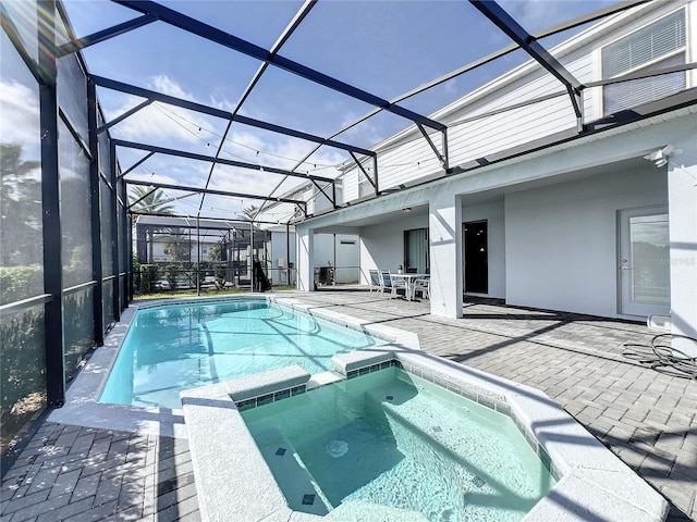 view of pool featuring a lanai, a patio, and an in ground hot tub