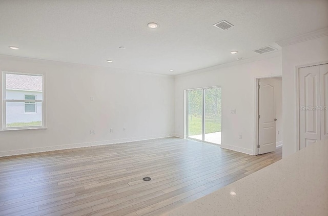 unfurnished room with crown molding, a textured ceiling, and light wood-type flooring