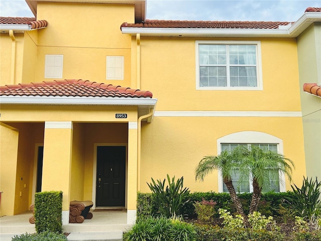 property entrance featuring a tile roof and stucco siding