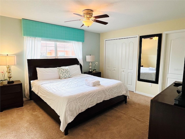 bedroom with light carpet, baseboards, a ceiling fan, and a closet