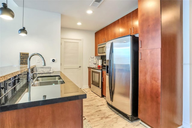 kitchen featuring hanging light fixtures, appliances with stainless steel finishes, sink, and light hardwood / wood-style flooring