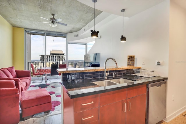 kitchen featuring decorative light fixtures, dishwasher, sink, dark stone countertops, and light wood-type flooring