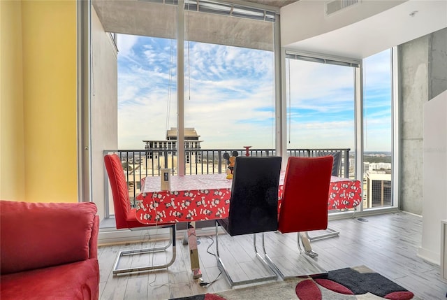 dining area with expansive windows, hardwood / wood-style flooring, and a wealth of natural light