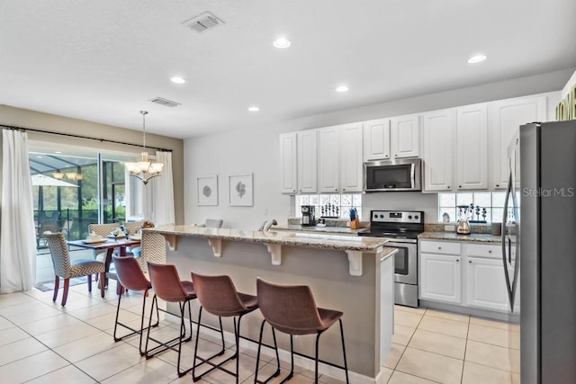 5220 Oakbourne Ave, Davenport, FL 33837 - kitchen featuring appliances with stainless steel finishes, white cabinetry, light stone countertops, a breakfast bar area, and recessed lighting
