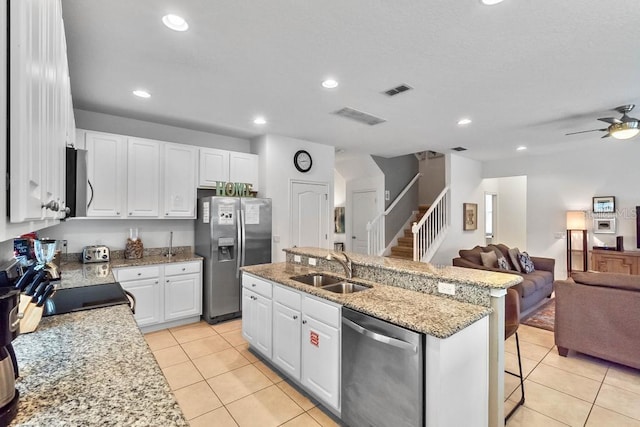 kitchen with light tile patterned flooring, stainless steel appliances, sink, and an island with sink