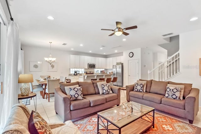 living room featuring ceiling fan with notable chandelier and light tile patterned floors