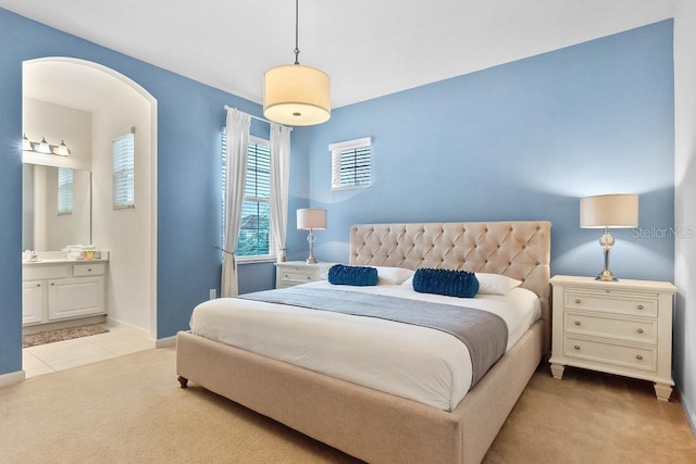 bedroom featuring ensuite bath and light carpet