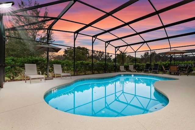 pool at dusk with a patio and glass enclosure