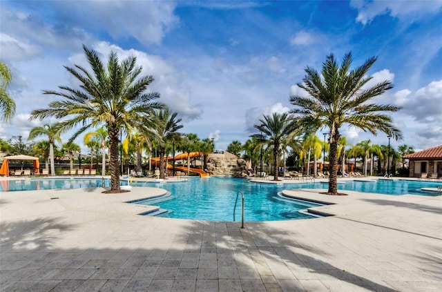 view of pool with a water slide and a patio