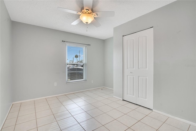 unfurnished bedroom featuring ceiling fan, light tile patterned flooring, a textured ceiling, and a closet