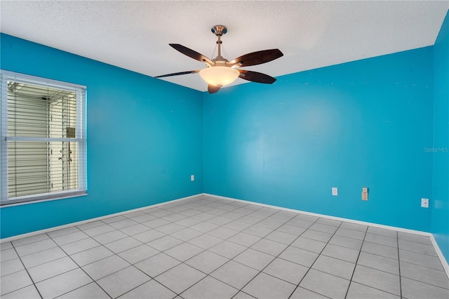 empty room featuring ceiling fan, light tile patterned flooring, and a textured ceiling