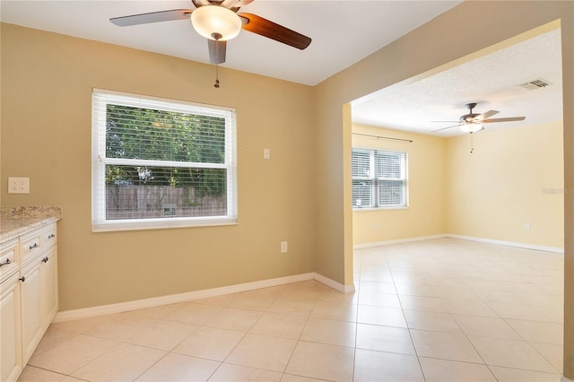 tiled empty room with a textured ceiling and ceiling fan