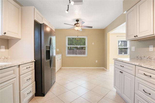 kitchen featuring light stone countertops, ceiling fan, a healthy amount of sunlight, and stainless steel refrigerator with ice dispenser