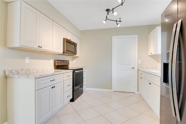 kitchen with white cabinets, stainless steel appliances, light stone countertops, and light tile patterned flooring