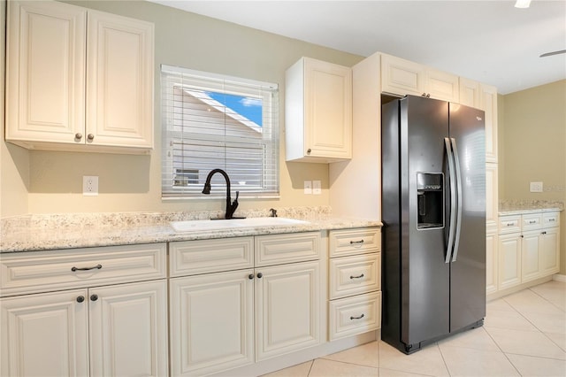 kitchen with light stone counters, sink, light tile patterned floors, and stainless steel refrigerator with ice dispenser