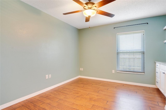 empty room featuring ceiling fan, light hardwood / wood-style floors, and a textured ceiling