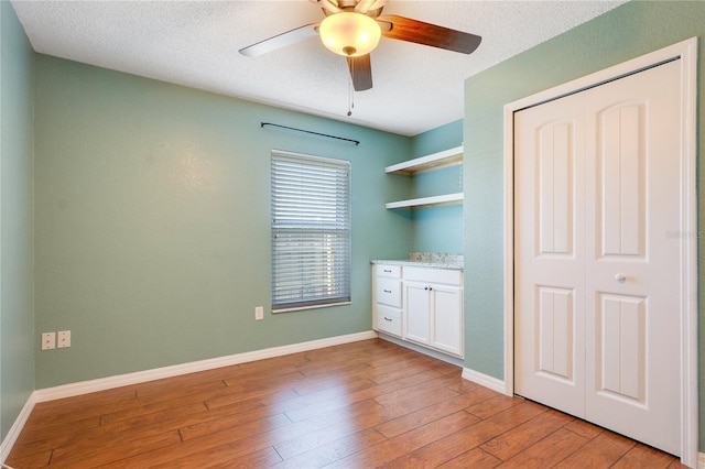 interior space featuring ceiling fan, a closet, light hardwood / wood-style floors, and a textured ceiling