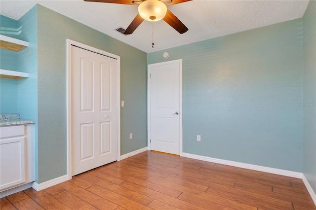 unfurnished bedroom featuring a textured ceiling, a closet, ceiling fan, and light hardwood / wood-style floors