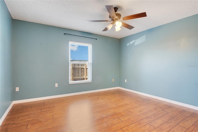 empty room featuring a textured ceiling, light wood-type flooring, and ceiling fan