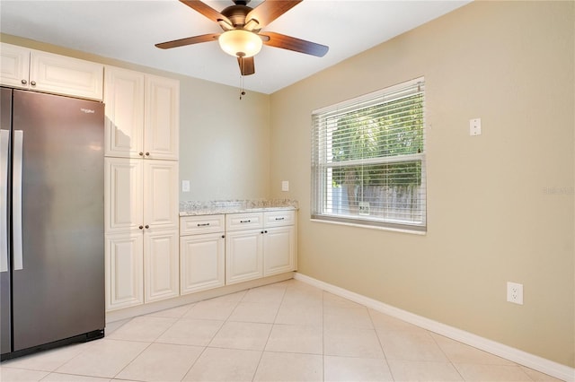 kitchen featuring stainless steel fridge, ceiling fan, light stone countertops, and light tile patterned floors