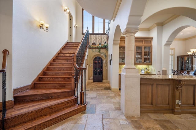 stairs with an inviting chandelier and ornamental molding