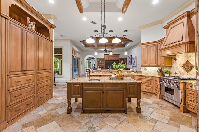 kitchen featuring sink, pendant lighting, a kitchen island with sink, stainless steel stove, and ornamental molding