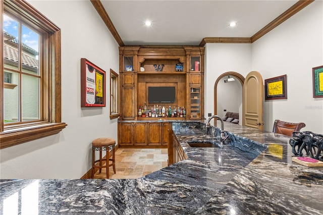 bar with ornamental molding, sink, and dark stone counters