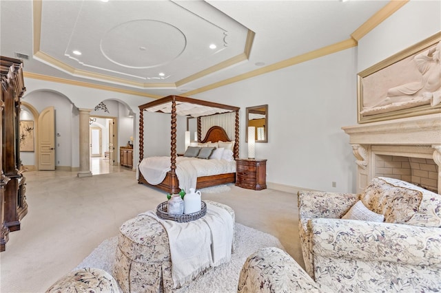 carpeted bedroom featuring ornamental molding, a tray ceiling, and decorative columns