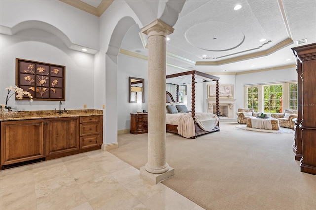 bedroom featuring light carpet, a raised ceiling, ornate columns, and crown molding