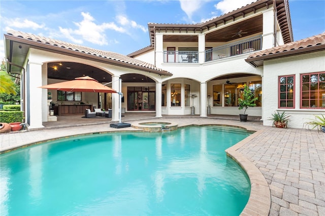 back of house with ceiling fan, a balcony, a patio, and a pool with hot tub