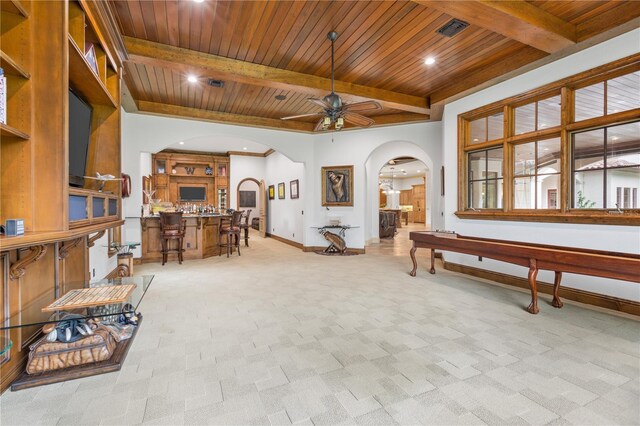 interior space featuring beamed ceiling, ceiling fan, light colored carpet, and wooden ceiling