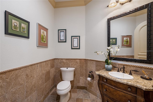 bathroom with vanity, toilet, tile walls, and ornamental molding