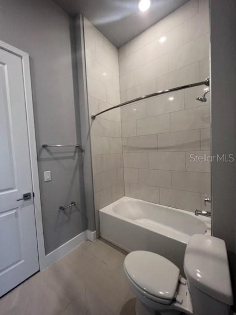 bathroom featuring toilet, tile floors, and tiled shower / bath