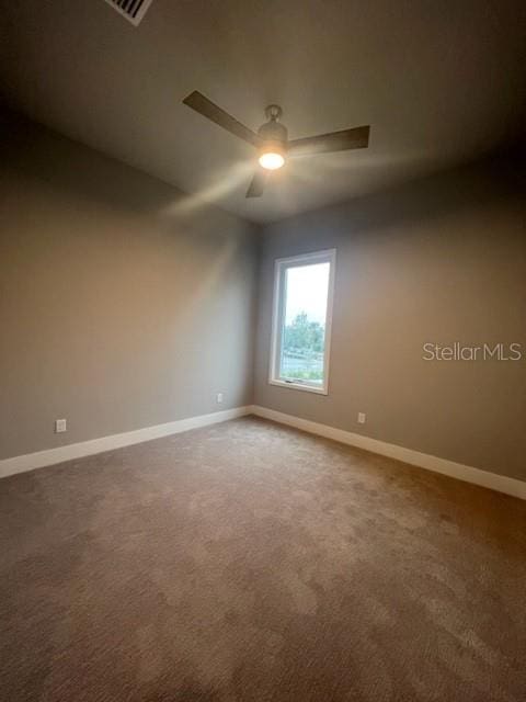 spare room with dark colored carpet and ceiling fan