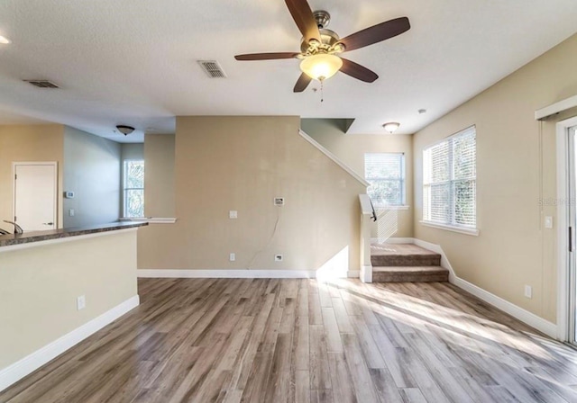 unfurnished living room featuring ceiling fan, sink, and light hardwood / wood-style flooring