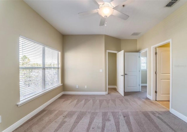 unfurnished bedroom featuring ceiling fan, light carpet, and multiple windows