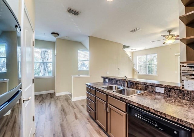 kitchen featuring black dishwasher, a healthy amount of sunlight, decorative backsplash, light wood-type flooring, and sink