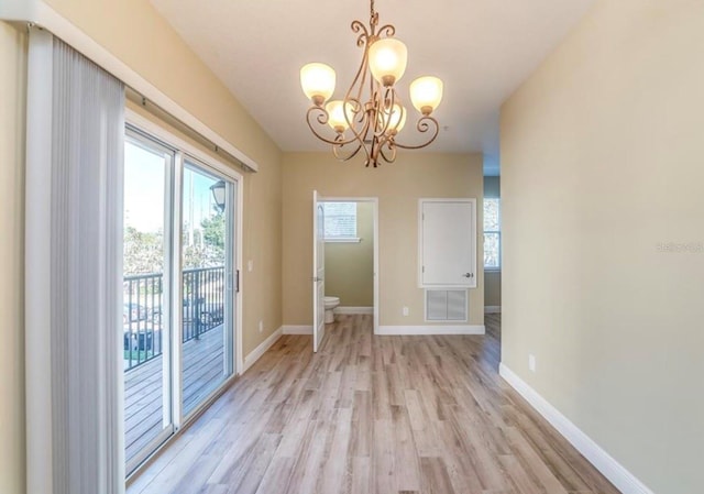 unfurnished dining area with an inviting chandelier and light hardwood / wood-style floors