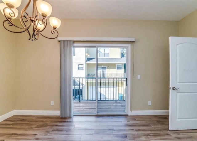 empty room with wood-type flooring and an inviting chandelier