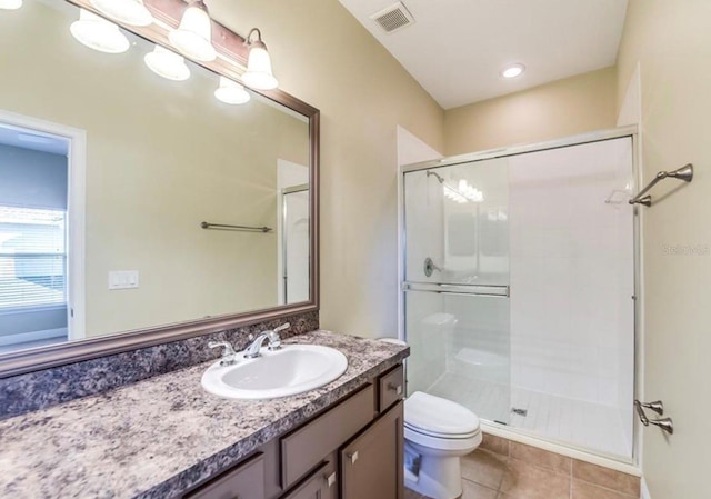 bathroom featuring toilet, vanity, tile patterned flooring, and walk in shower