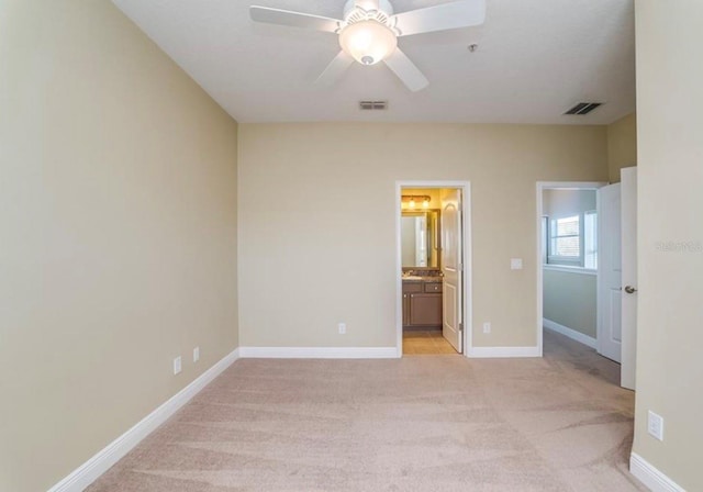 unfurnished bedroom with ceiling fan, light colored carpet, and connected bathroom