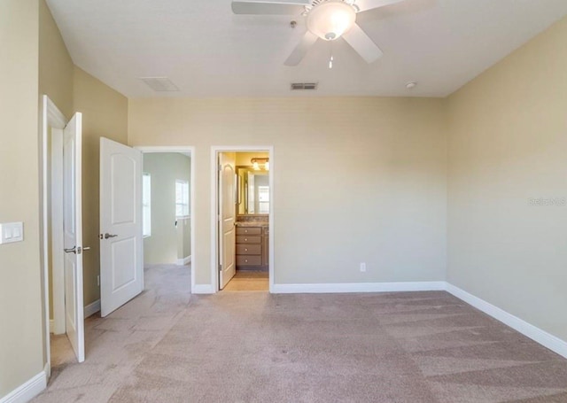 unfurnished bedroom featuring light carpet, ceiling fan, and ensuite bath