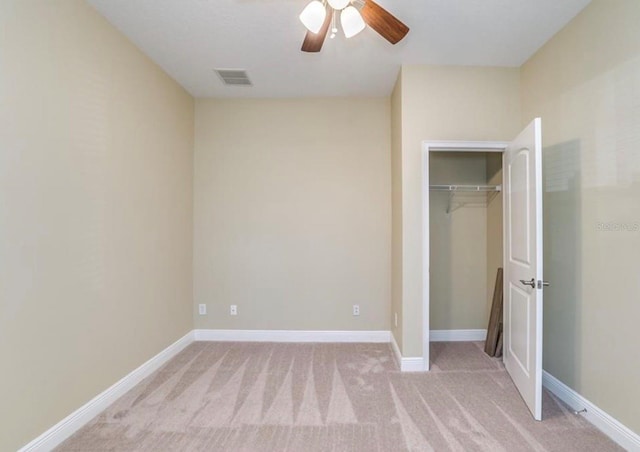 unfurnished bedroom with ceiling fan, light colored carpet, and a closet