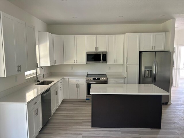 7539 Bernal Dr, Sebring, FL 33872 - kitchen featuring appliances with stainless steel finishes, a sink, white cabinets, light countertops, and a center island