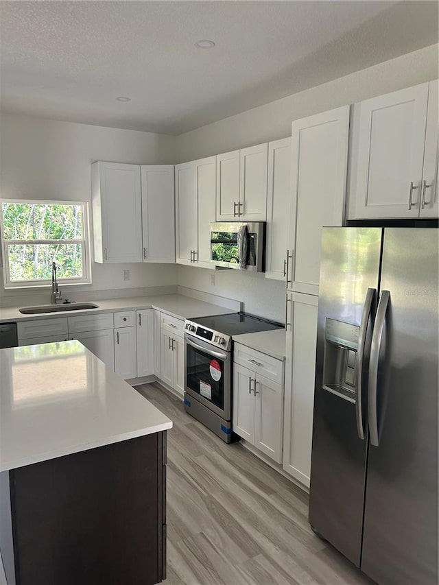 7539 Bernal Dr, Sebring, FL 33872 - kitchen with stainless steel appliances, a sink, light wood-style floors, light countertops, and white cabinets